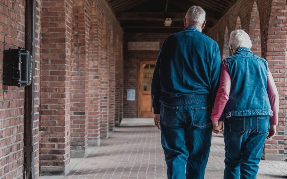 Elderly couple walking away, hand in hand.