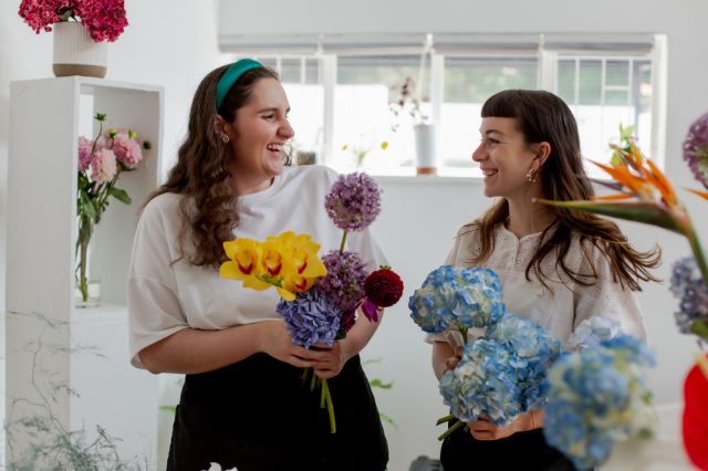two women with flowers smiling at each other